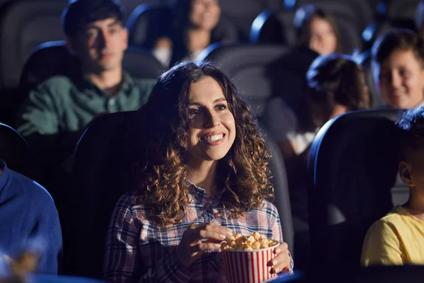 Молодая смеющаяся женщина ест попкорн в кино. — стоковое фото