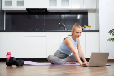 Spor kadını ev içi eğitim için modern dizüstü bilgisayar kullanıyor.