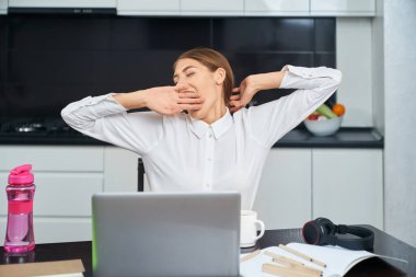 Evde çalışırken esneyen bir kadın.