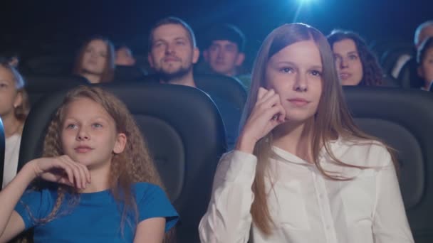 Mladá smějící se dívka se zubní rovnátka v kině. — Stock video
