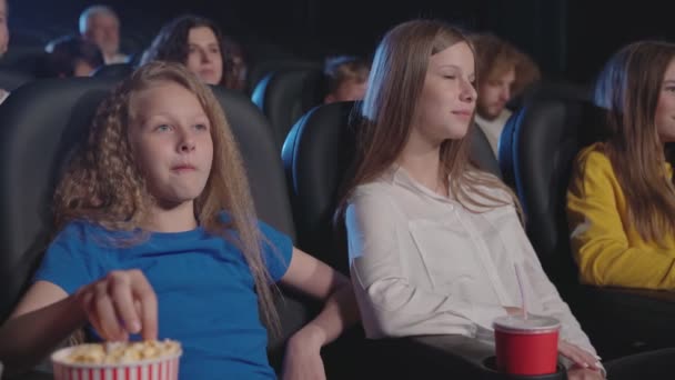 Молодая смеющаяся девушка с младшей сестрой в кино. — стоковое видео