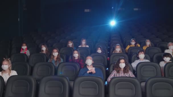 Sinemada yüz maskesi takan genç seyirciler. — Stok video