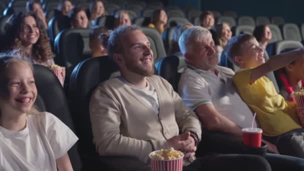 아이들과 어른들이 영화관에서 만화를 즐긴다. — 비디오