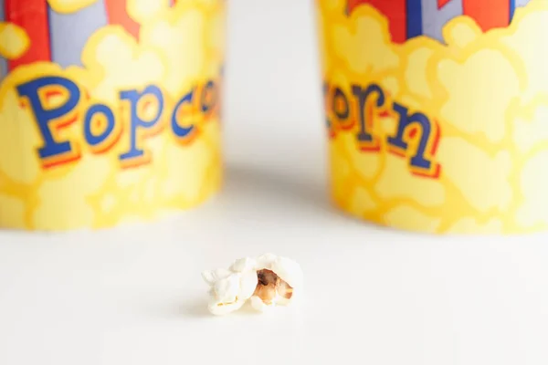 Ein Stück Popcorn in der Nähe von zwei Pappbechern. — Stockfoto