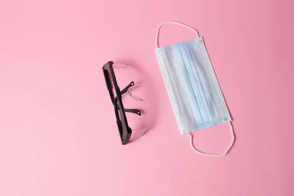 Svart medicinska glasögon och mask på rosa bakgrund. — Stockfoto
