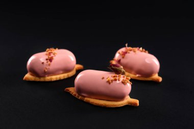 Siyah üzerine izole edilmiş ayna yüzeyi olan pembe kekler.