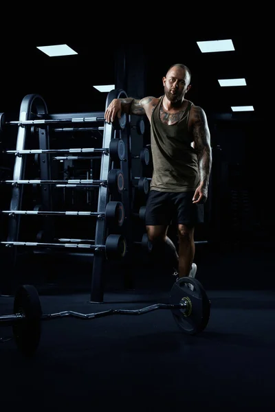 Tatuerad manlig kroppsbyggare poserar i gym. — Stockfoto