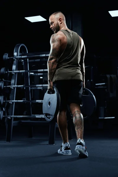 Muskulös manlig kroppsbyggare som håller vikter. — Stockfoto