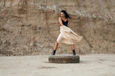 Açık havada eski lastiğin üzerinde duran iç çamaşırlı çekici bir kadın.