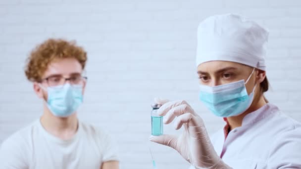 Молодий чоловік готується до ін'єкційної вакцини covid-2019 у клініці . — стокове відео