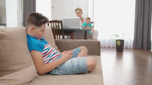 Vrouw met twee zonen die thuis aan laptop werken — Stockvideo