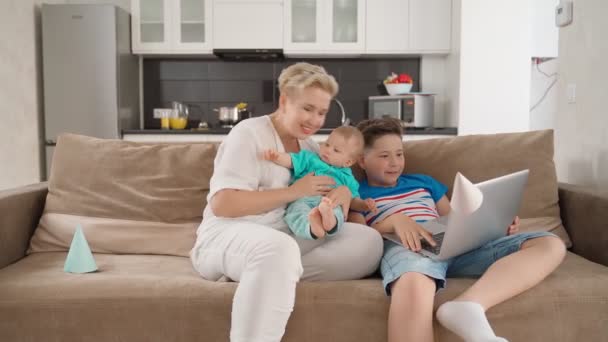 Mère souriante jouant sur le canapé avec ses deux fils — Video