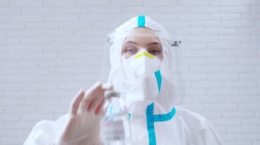 Korunma giysisi içinde Coronavirus 'a karşı aşı taşıyan bir sağlık görevlisi..
