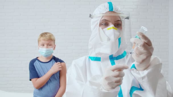 Krankenschwester in Schutzmaske und Anzug gibt Impfung gegen Coronavirus für widerspenstigeren Jungen. — Stockvideo