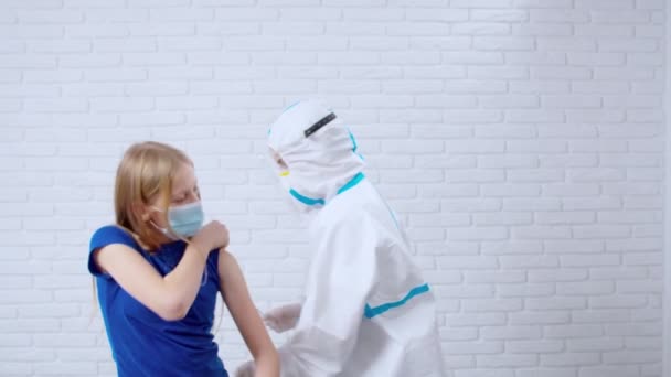 Doctor in anti-virus suit making injection for teenage girl. — Stock Video