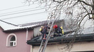 İtfaiyeciler yanmış çatıda çalışıyor..