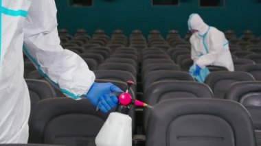İki işçi sinema salonunda sandalye temizliyor..