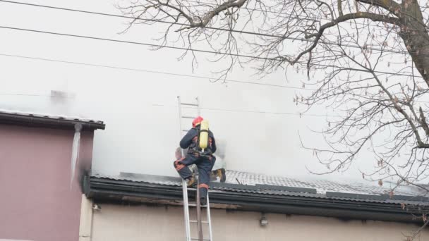 Pemadam kebakaran dalam helm memadamkan api di atap. — Stok Video