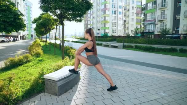 Fitnesswoman stretching gambe su panchina in città. — Video Stock