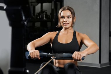 Spor salonunda ağırlık egzersizi yapan genç bir kadın..