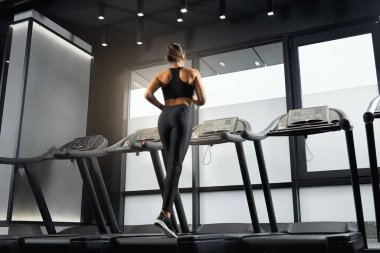 Güzel genç bir kadın spor salonunda kardiyo yapıyor..