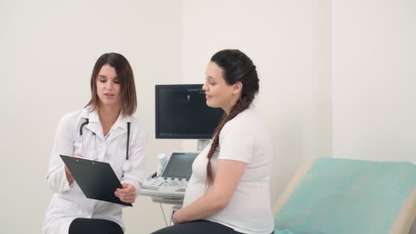 Ginecologista com prancheta conversando com mulher grávida — Vídeo de Stock