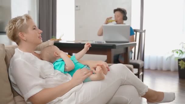 Vrouw spelen met peuter terwijl tiener met behulp van laptop — Stockvideo