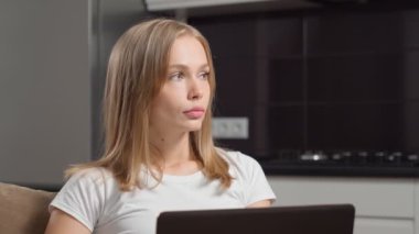 Evde kalıp dizüstü bilgisayarla uğraşan odaklanmış bir kadın.