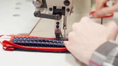 Dikiş makinesinde nefes maskesi takan terzi.