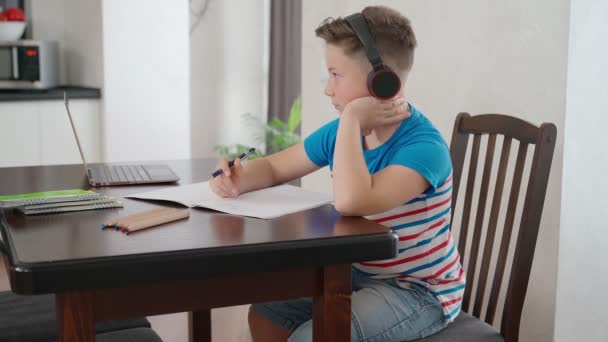 Chlapec používající notebook a sluchátka pro studium doma — Stock video
