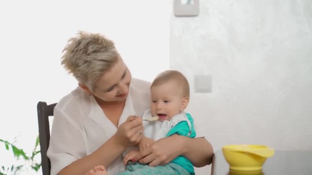 Kvinna utfodring barn med gröt på kök — Stockvideo