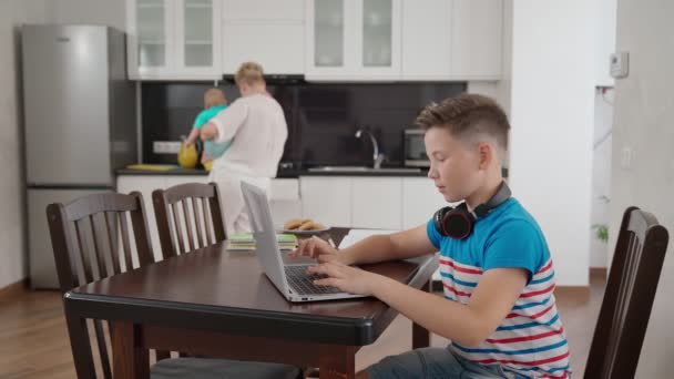 Mère préparant le dîner pendant que le fils étudie sur ordinateur portable — Video