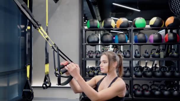 Mujer joven en cuclillas con correas de fitness. — Vídeos de Stock