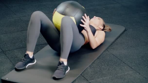 Νεαρή γυναίκα κάνει άσκηση με μεγάλη μπάλα του αθλητισμού. — Αρχείο Βίντεο