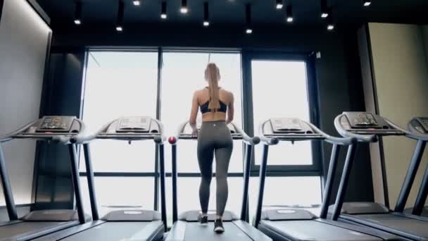 Karcsú nő gyakorolja a futópadon. — Stock videók