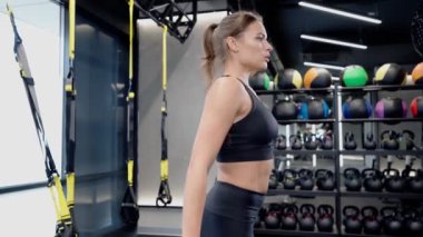 Sportif kadın trx sisteminde çömeliyor..