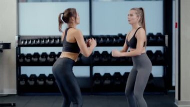 Gülümseyen kadınlar spor salonunda çömeliyor..