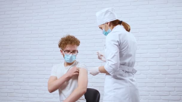 Enfermera joven que da la vacuna covid-2019 para el hombre joven. — Vídeos de Stock