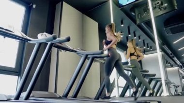 Modern spor salonunda koşu bandında egzersiz yapan genç kadınlar..