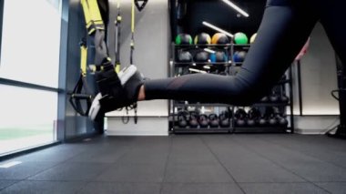 TRX 'le çömelmiş bir kadın.