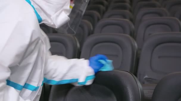 Trabajador limpiando sillas con desinfectantes en el cine. — Vídeo de stock