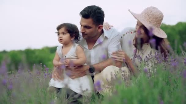 Молода усміхнена сім'я сидить у лавандовому полі — стокове відео