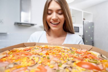 Heyecanlı kadın elinde lezzetli pizzayla.