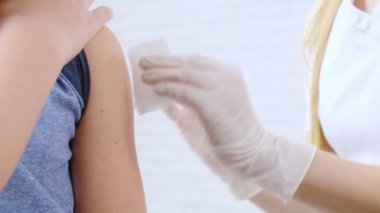 Lastik eldivenli hemşire klinikteki çocuğa iğne yapıyor..