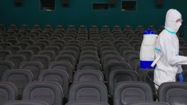 Boş sinema salonunda dezenfekte yapan bir işçi..