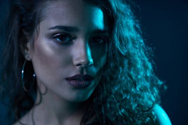 Neon ışıklarının altında poz veren kadın.