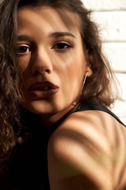 Güzel kız izole edilmiş beyaz tuğla duvar yapıyor..