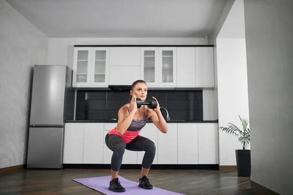 Mujer joven entrenando piernas en casa usando pesas. — Foto de Stock