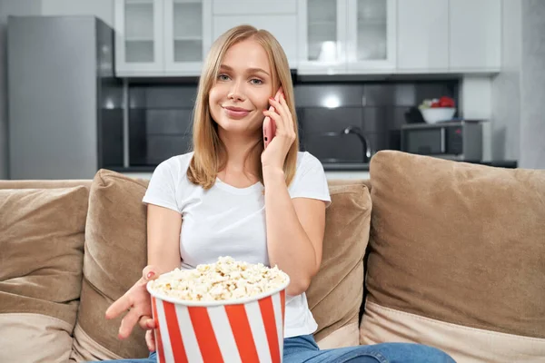 Attractive woman talking on mobile and eating popcorn — Stock Photo, Image