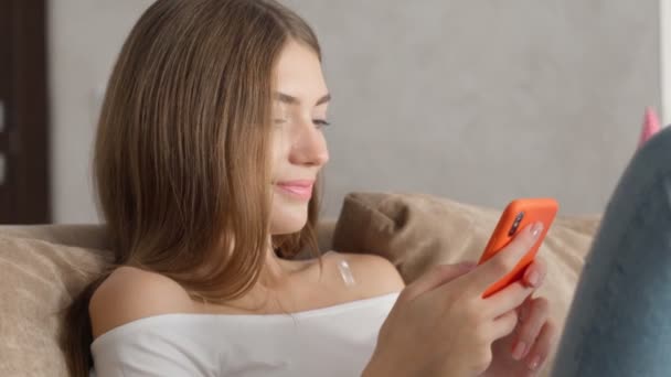 Młoda kobieta śmieje się podczas korzystania ze smartfona w domu. — Wideo stockowe